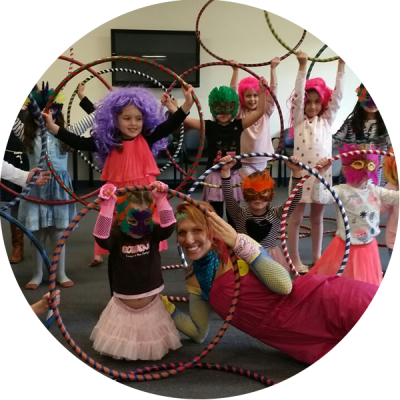Donna Sparx with kids and hula hoops at hula hoop kids party. Kids are wearing wigs and masks.